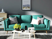 Teal sofa in a living room with decorative pillows and a coffee table.
