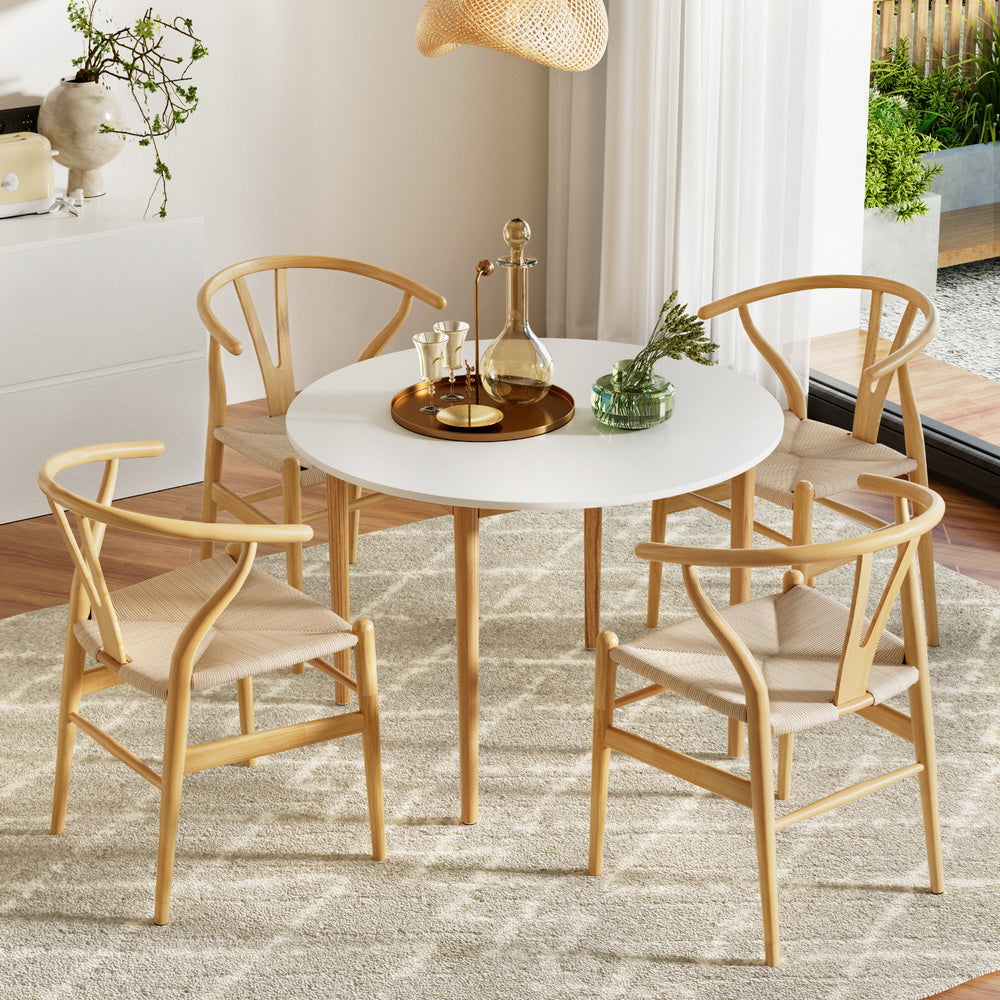 Round dining table with four wooden chairs in a modern living room.