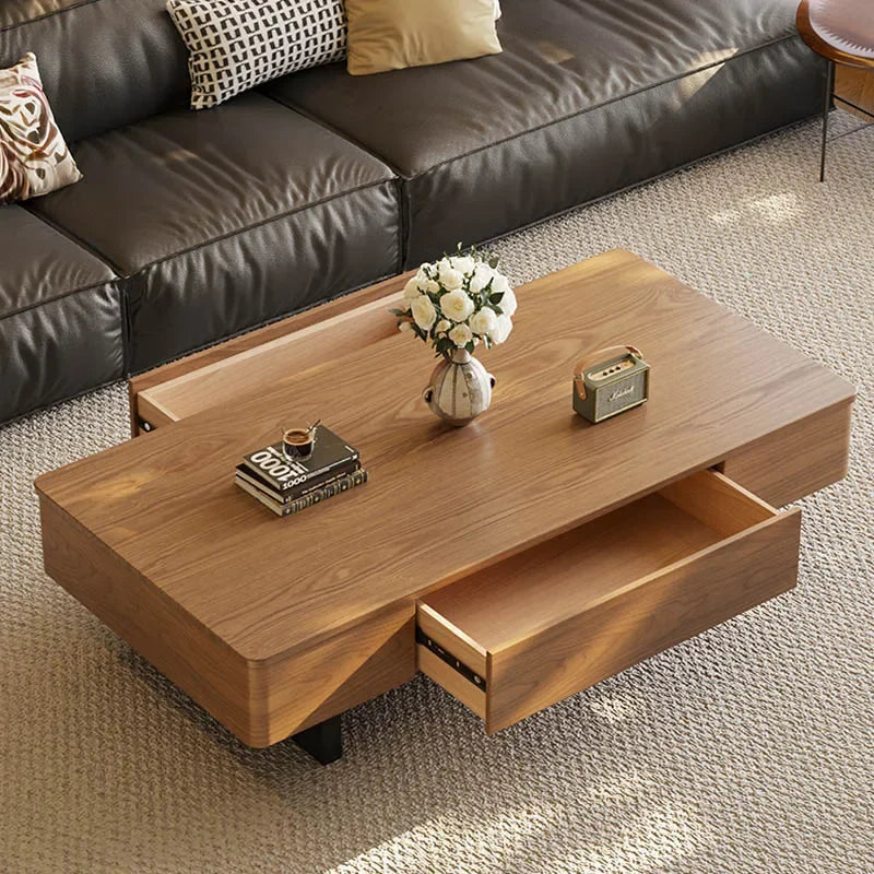Wooden coffee table with a vase of flowers and books in a living room setting.