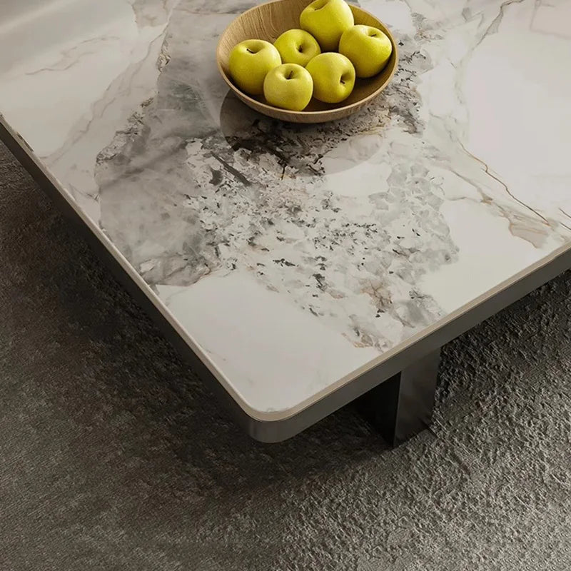 Marble-patterned coffee table with a bowl of green apples on a dark surface