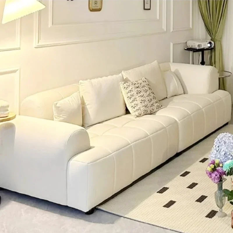 White sofa in a living room with decorative pillows and a rug.