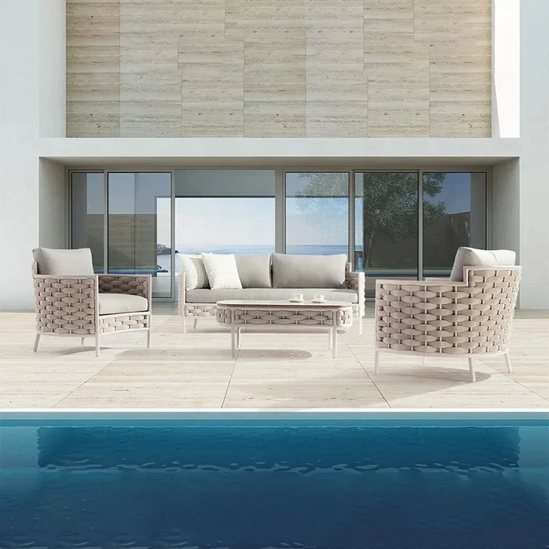 Outdoor patio set with sofa and chairs by a poolside.