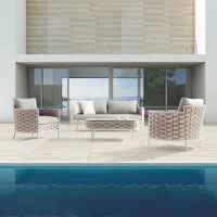 Outdoor patio set with sofa and chairs by a poolside.