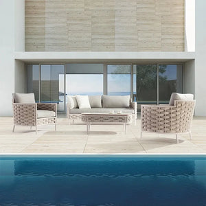 Outdoor patio set with sofa and chairs by a poolside.