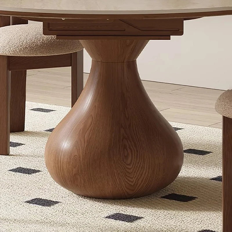 Wooden dining table with a unique base design on a patterned rug.