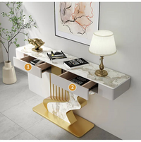 Modern console table with marble design and gold accents, featuring drawers and decorative items.