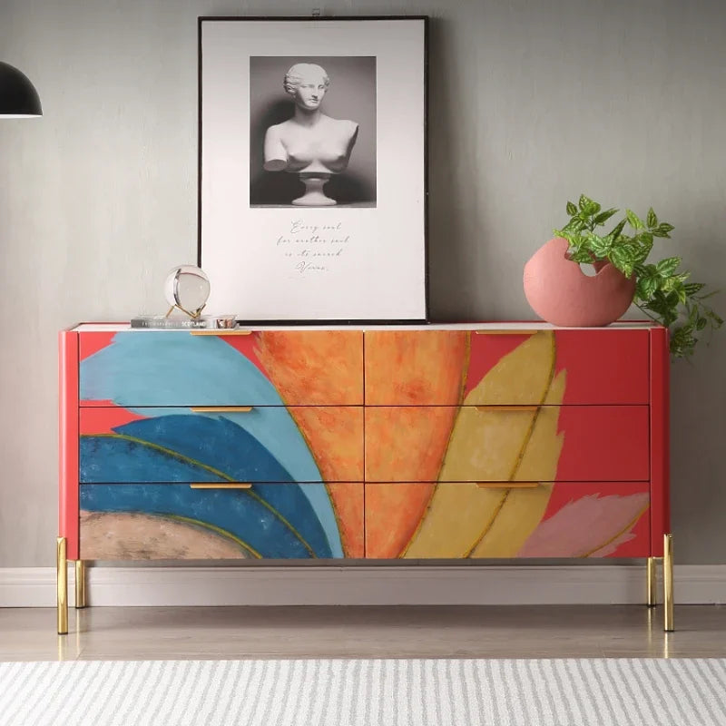 Colorful dresser with abstract design in a room with a framed picture and plant.