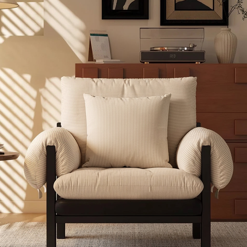 Woman sitting on a cushioned chair reading a book in a cozy room.