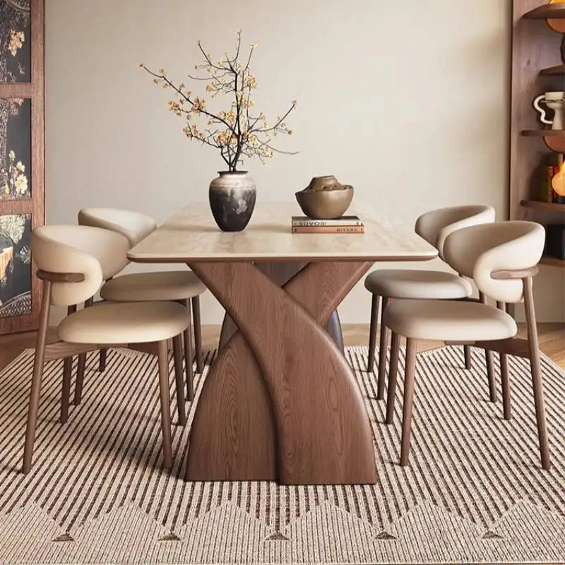 Dining room with a modern wooden table and chairs, decorated with vases and books.