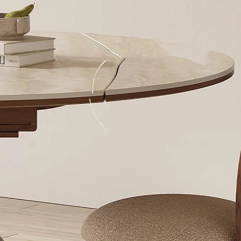 Round dining table with a marble-like top and wooden base, set against a neutral wall.
