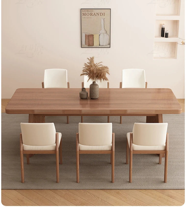 Dining room setup with a wooden table and chairs in a well-lit room.