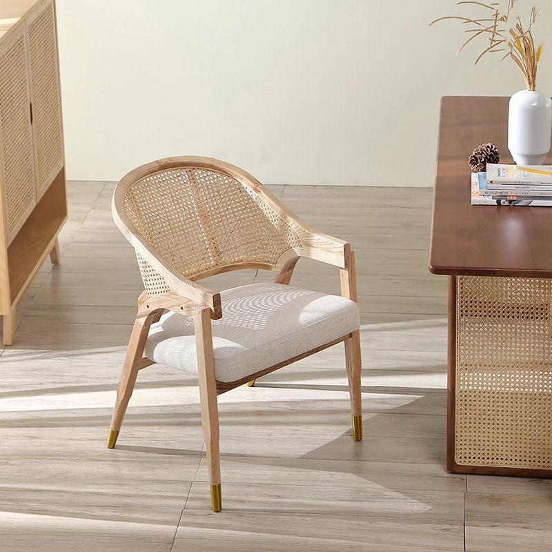 Wicker chair with white cushion in a room with wooden floor and furniture.