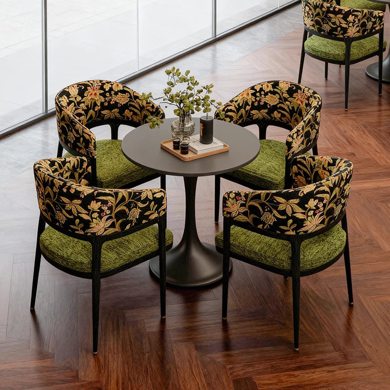 Four chairs with floral patterns and green cushions around a round table in a modern interior setting.