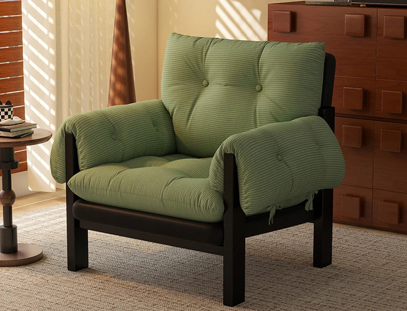 Green futon chair in a room with wooden furniture and a window.
