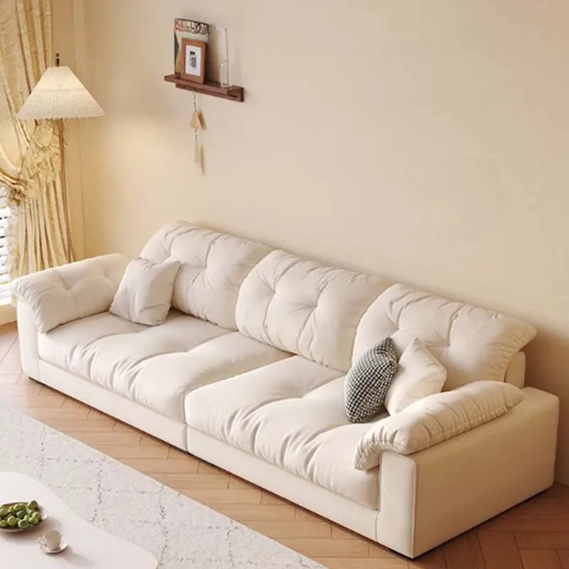 White sectional sofa in a living room with decorative pillows and a lamp.