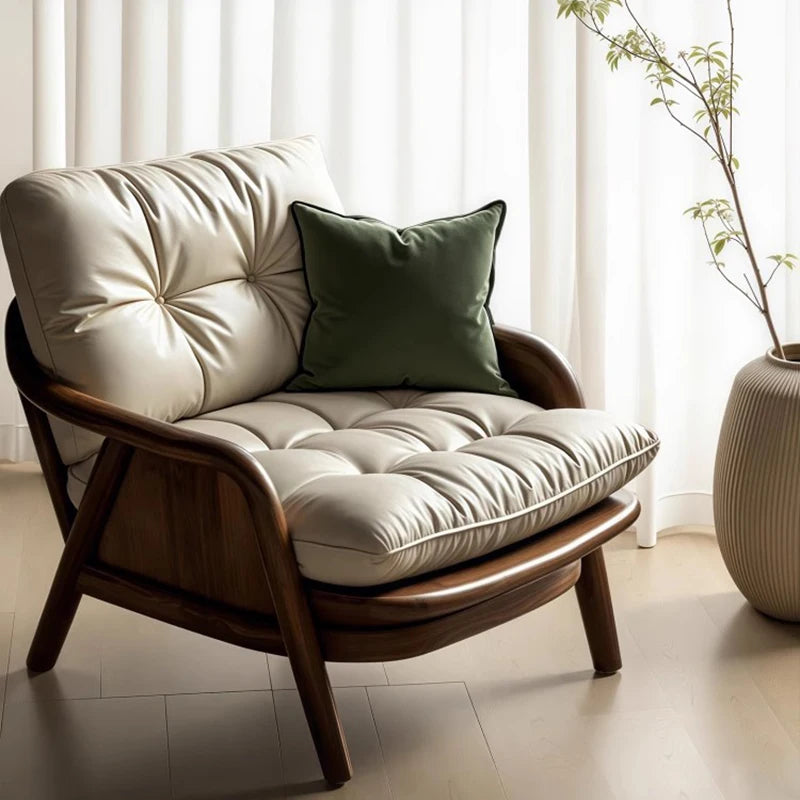 Wooden armchair with beige cushions and a green pillow in a bright room.