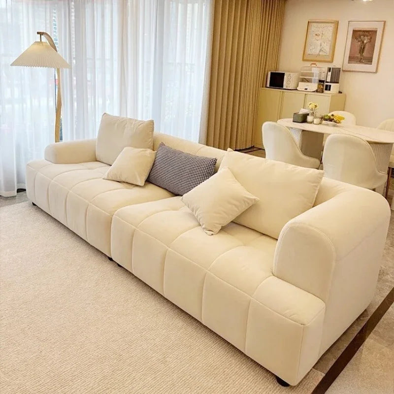 Beige sofa in a living room with a lamp and table in the background