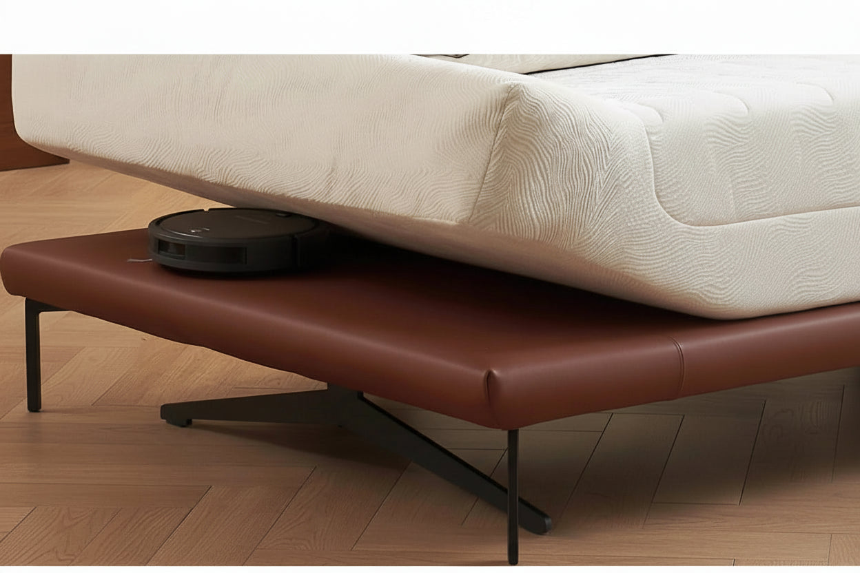 Robotic vacuum cleaner on a brown bench with a white mattress in the background