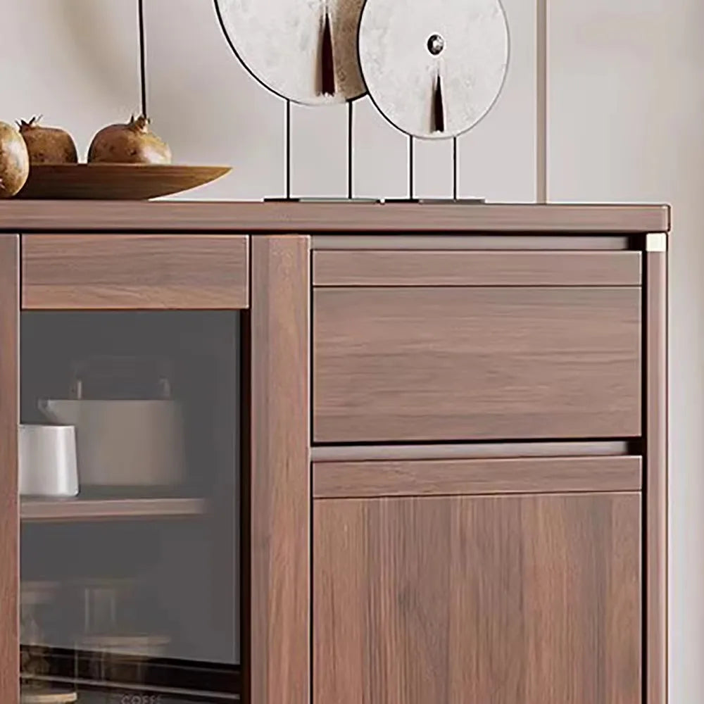 Wooden sideboard with glass door and drawers against a neutral wall.