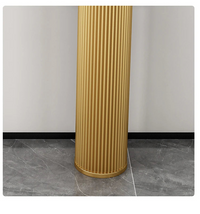 Gold cylindrical column with ribbed texture on a gray floor and white wall background