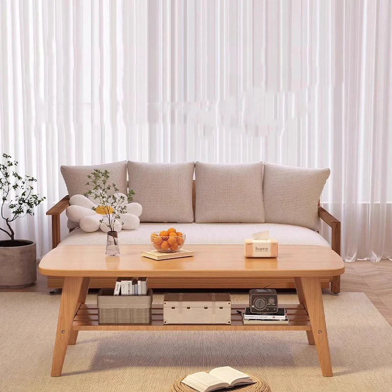 Living room with a wooden coffee table and sofa against sheer curtains.