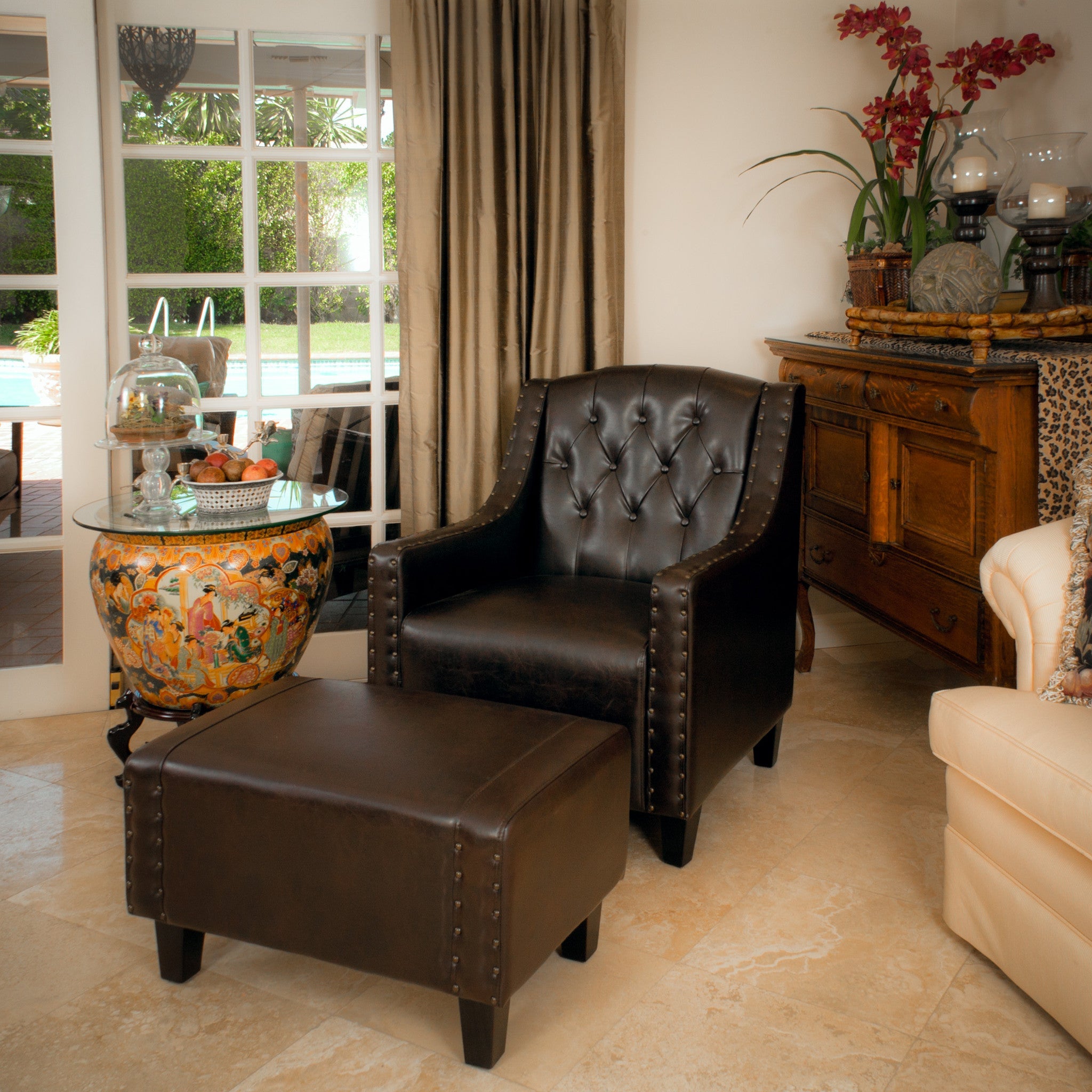 Brown leather armchair and ottoman in a living room setting with decorative items.