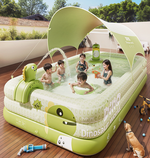 Children playing in a dinosaur-themed inflatable pool on a wooden deck with a dog nearby.
