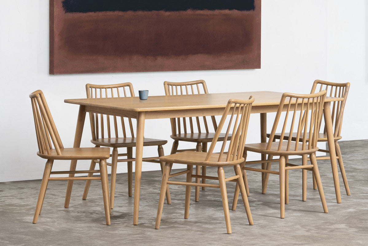 Wooden dining table with six chairs in a room with abstract art on the wall.