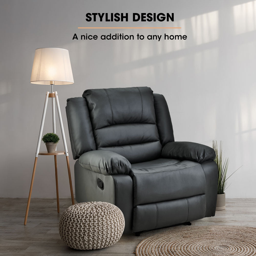 Gray recliner chair in a room with a lamp and small table.