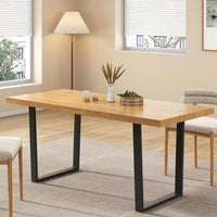Wooden dining table with black metal legs in a room with chairs and decor.