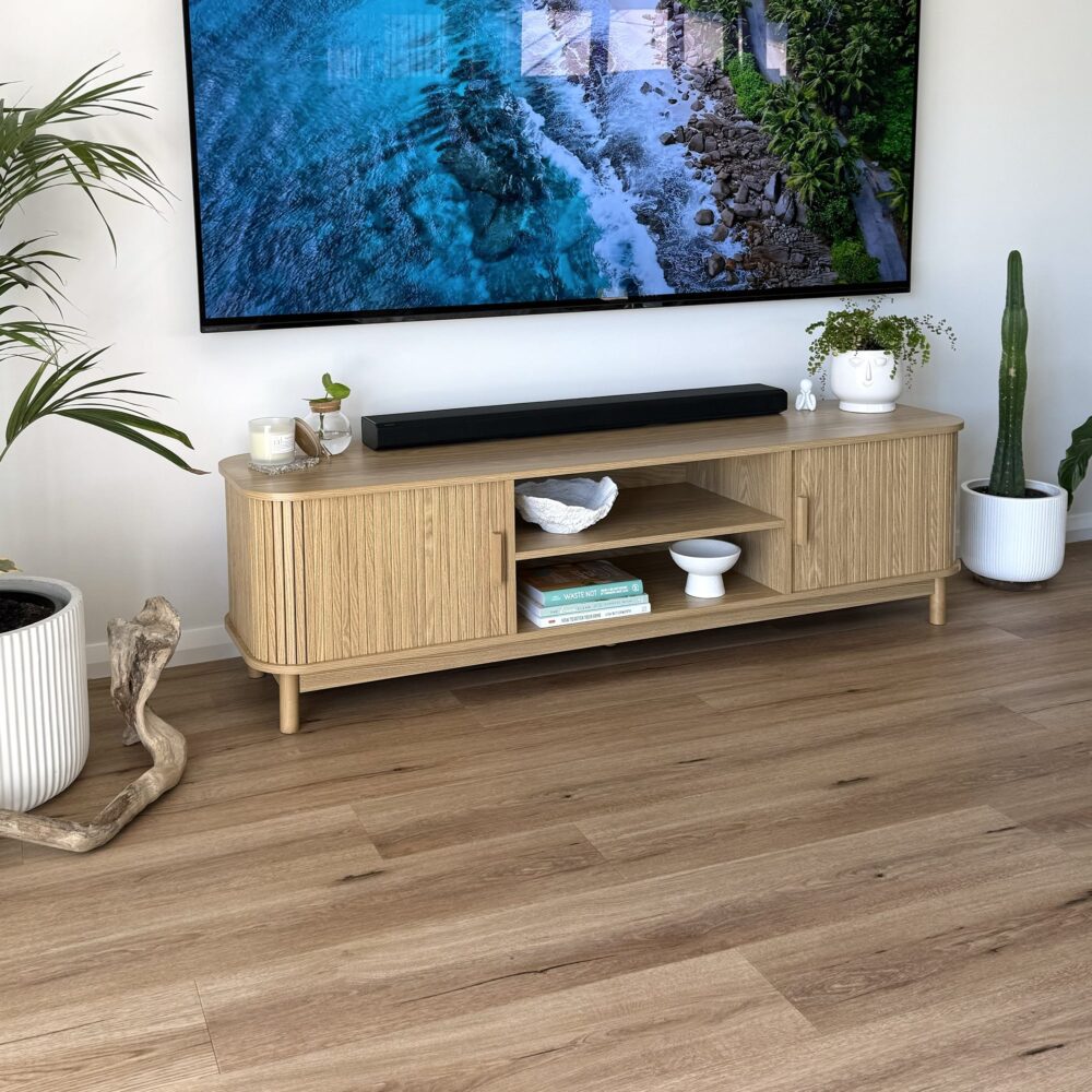 Wooden TV stand with a mounted television displaying a nature scene, surrounded by decorative items.