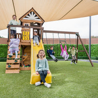 Children playing on a wooden playground set with slides and swings.