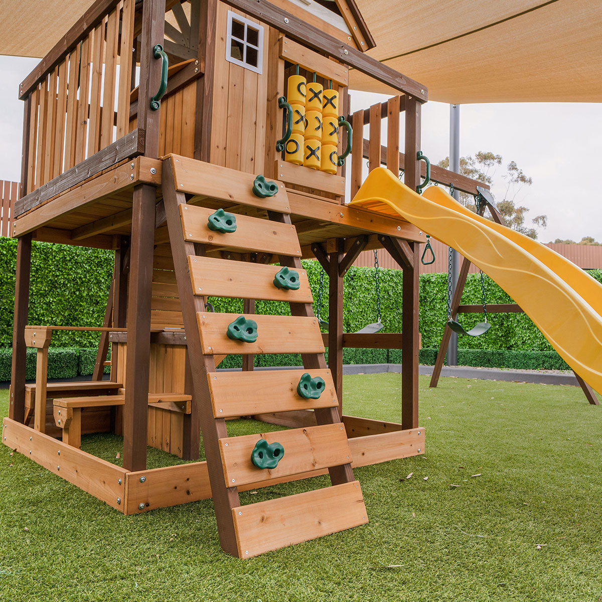 Wooden playset with a yellow slide on a grassy area