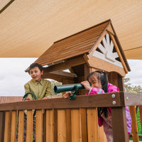 Two children playing with a telescope on a wooden playhouse