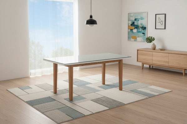Dining table with glass top and wooden legs against a neutral wall.