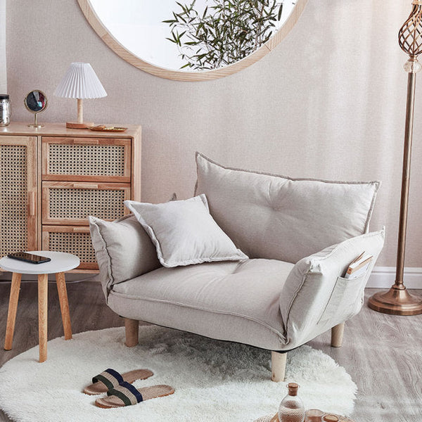 Light gray sofa in a living room with wooden cabinet and round mirror.
