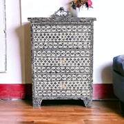 Decorative chest of drawers with mosaic pattern on a wooden floor.