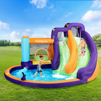 Children playing in an inflatable water park with a slide and pool on a grassy field.