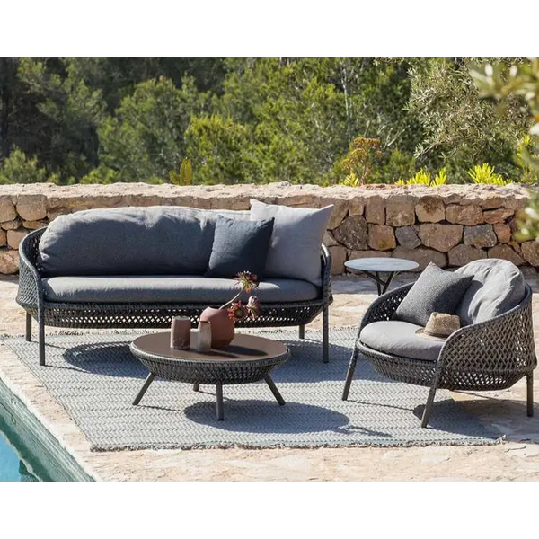Outdoor patio furniture set with a stone wall and greenery in the background