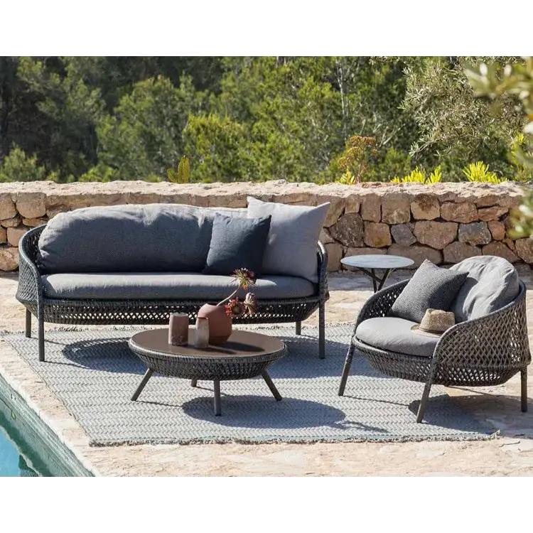 Outdoor patio furniture set with a stone wall and greenery in the background