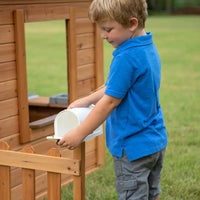 Young boy standing in natural cedar wood aspen cubby house with flower pot holders