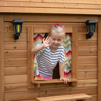 Little girl looking out of natural cedar wood backyard discovery aspen cubby house with flower pot holders