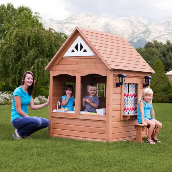 Woman and two children playing in natural cedar wood aspen cubby house with flower pot holders