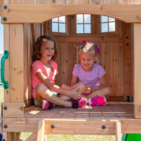 Two girls sitting in a wooden playhouse at backyard discovery montpelier play centre set