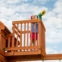 Young girl standing on raised clubhouse of backyard discovery skyfort ii play centre