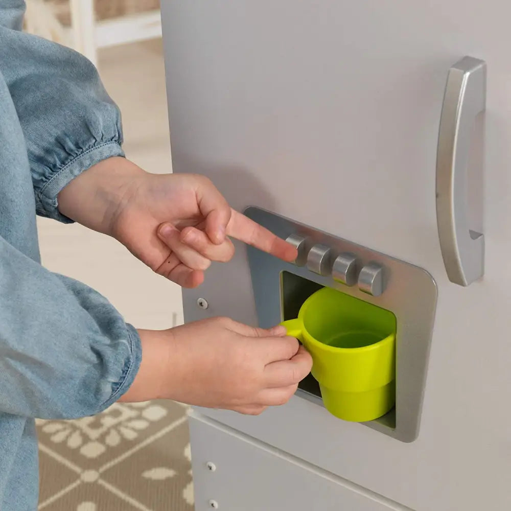 Child opening green cup door on doll cottage kitchen - perfect for young chefs