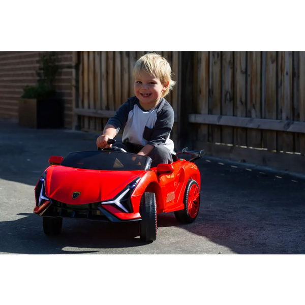 Little boy riding on red ferrari inspired 12v ride-on electric car