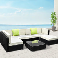 Gardeon outdoor sofa set with black and white wicker couch, green pillows, and tempered glass table