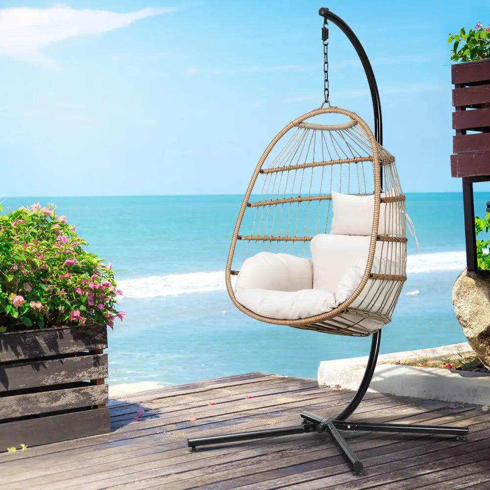 Gardeon foldable wicker swing egg chair with steel stand overlooking ocean