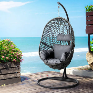 Gardeon rattan pod swing chair with stand and cushion - black/grey featuring a black hanging chair on a wooden deck